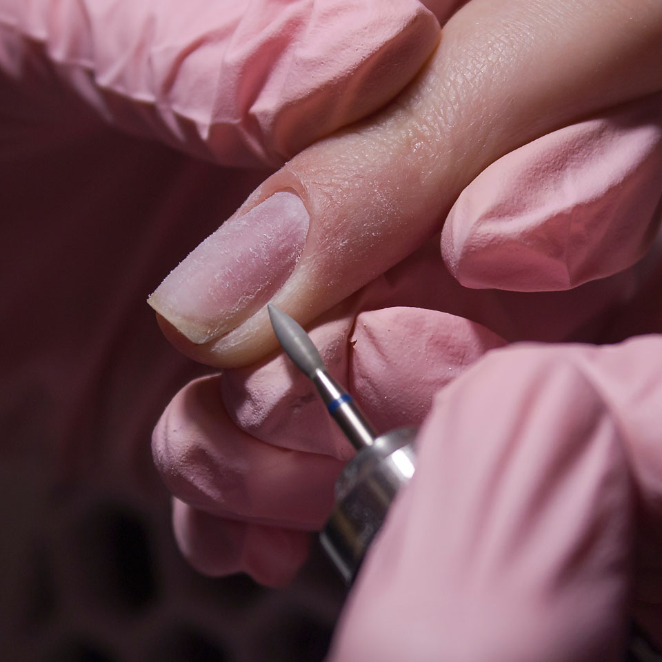 Nail technician carrying out a manicure using an electric filing tool